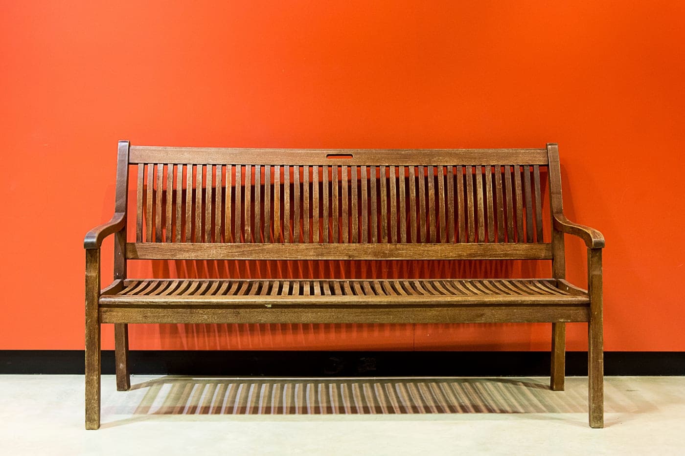 A simple wooden bench standing in front of a plain painted wall