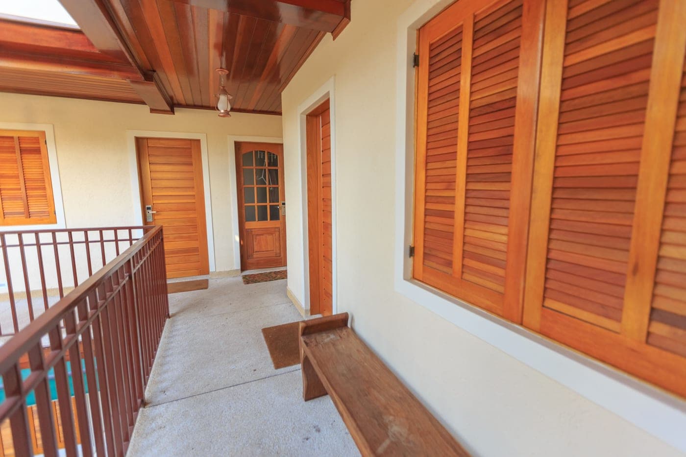 An empty bench in an indoor hallway with wooden shutters and doors