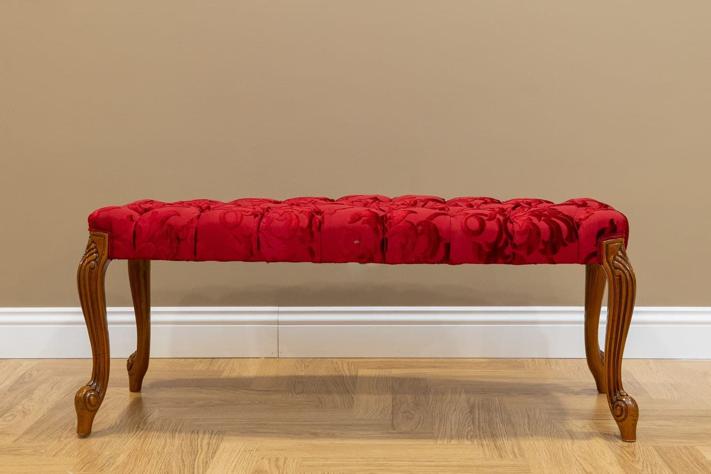 An upholstered bench with a padded seat against a plain wall