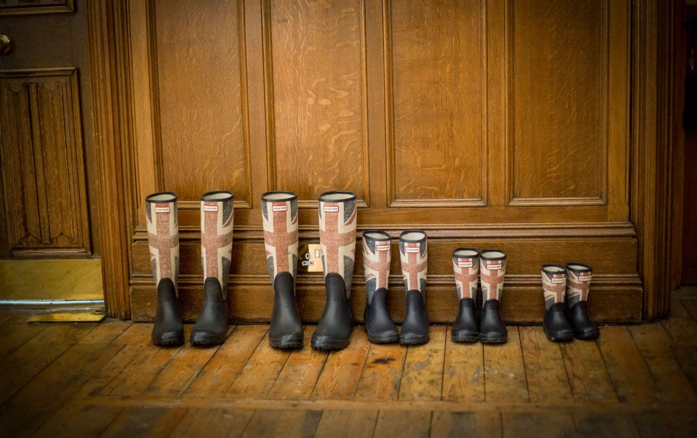 A mudroom bench with woven baskets beneath it and boots on the floor