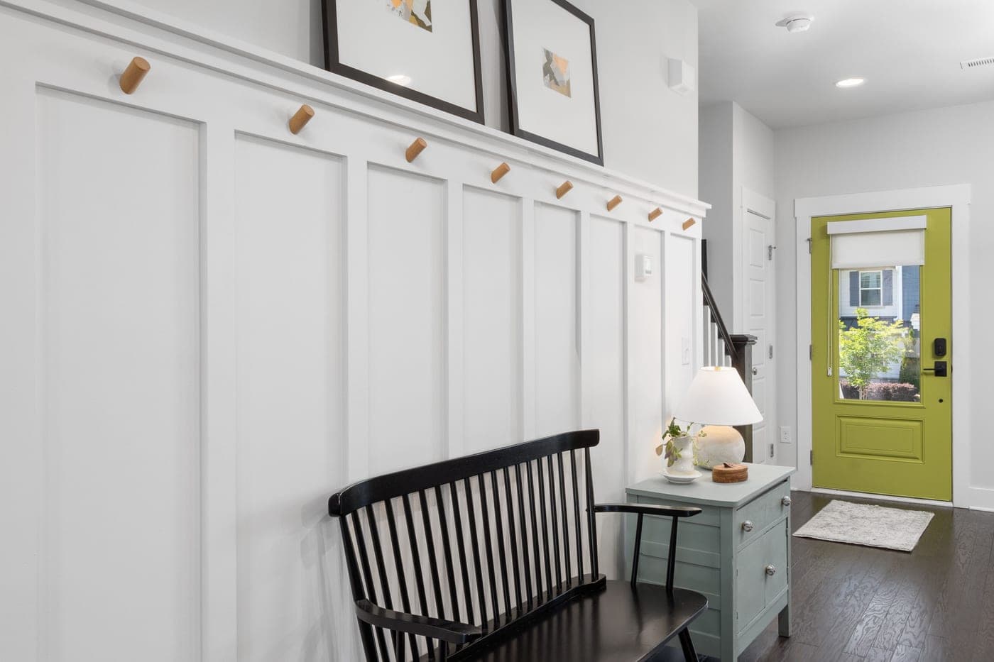 An entryway with a green front door and a black bench beside it