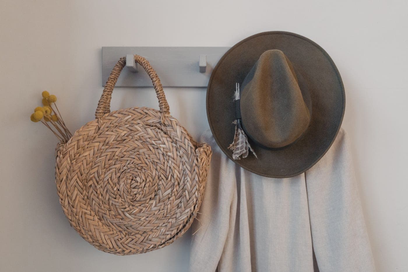 A tall coat stand against an entryway wall with hooks at head height