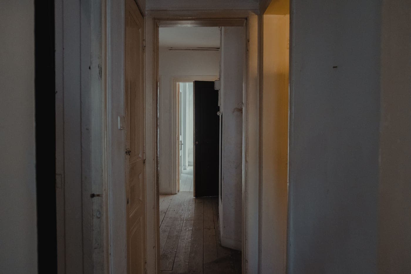 A dimly lit apartment hallway with wooden doors