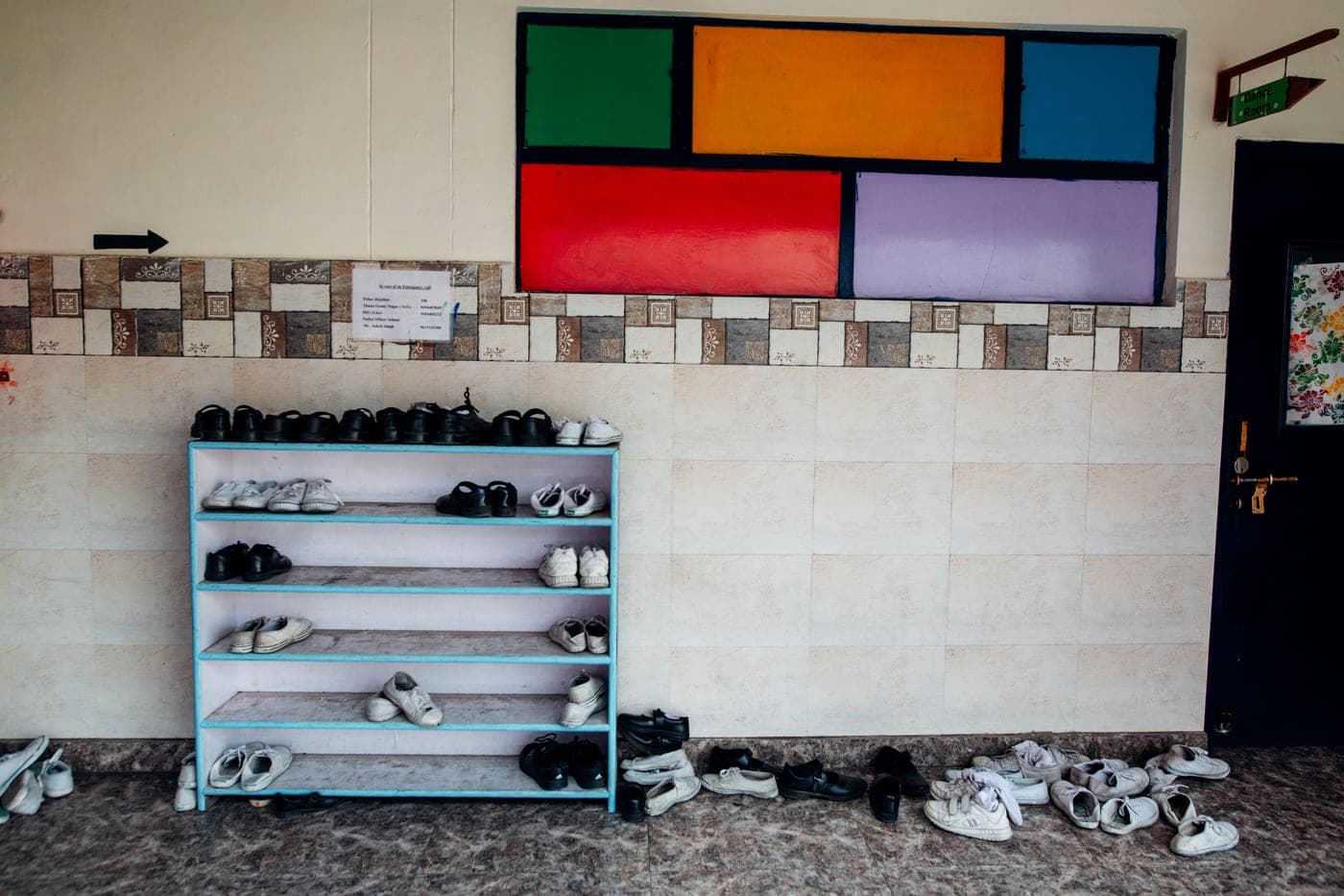 A hallway with a colorful wall and a neat row of shoes on a rack