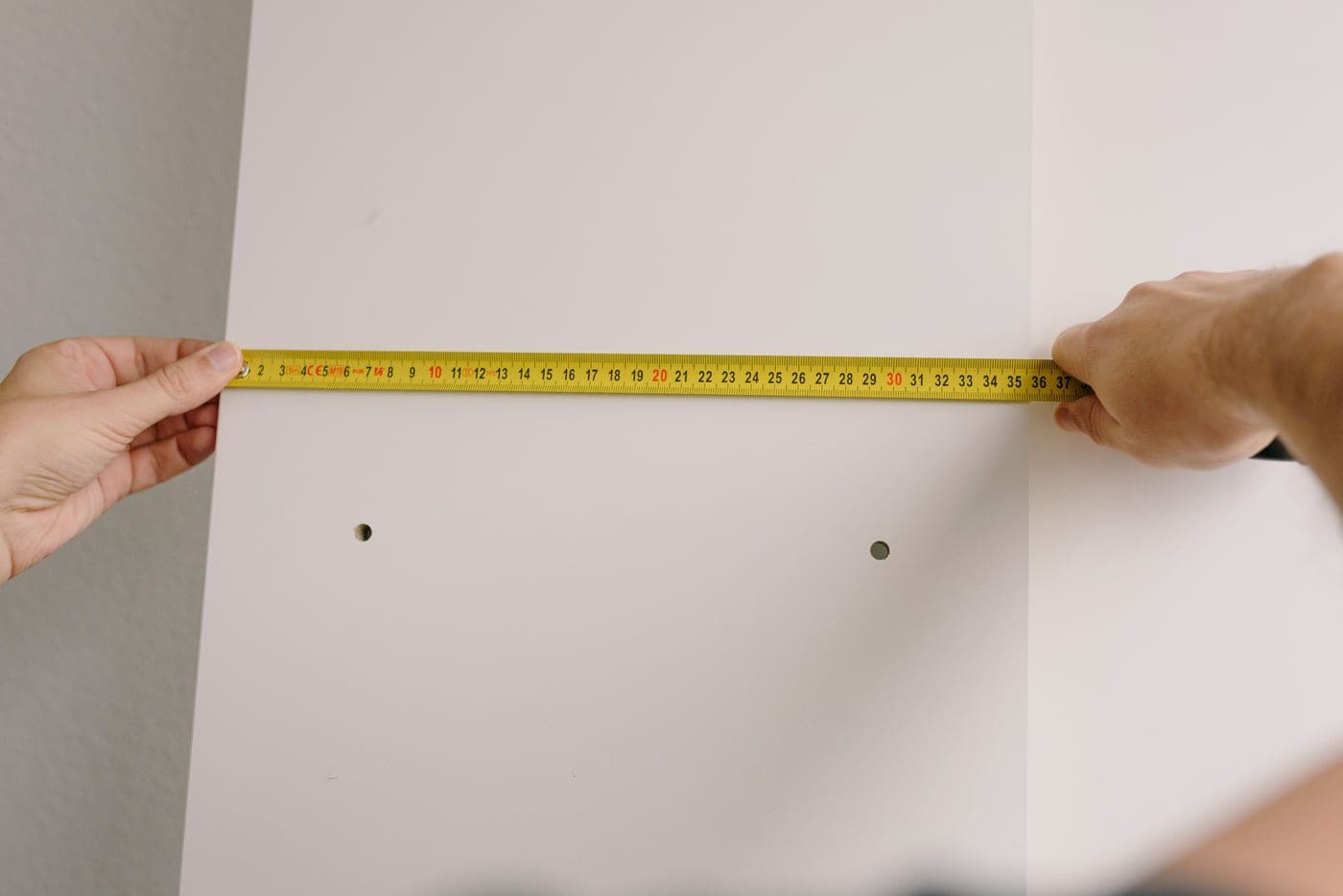 A tape measure held against a wall at home
