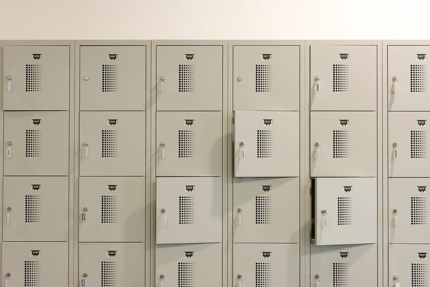 A mudroom with lockers, hanging coats and boots on the floor