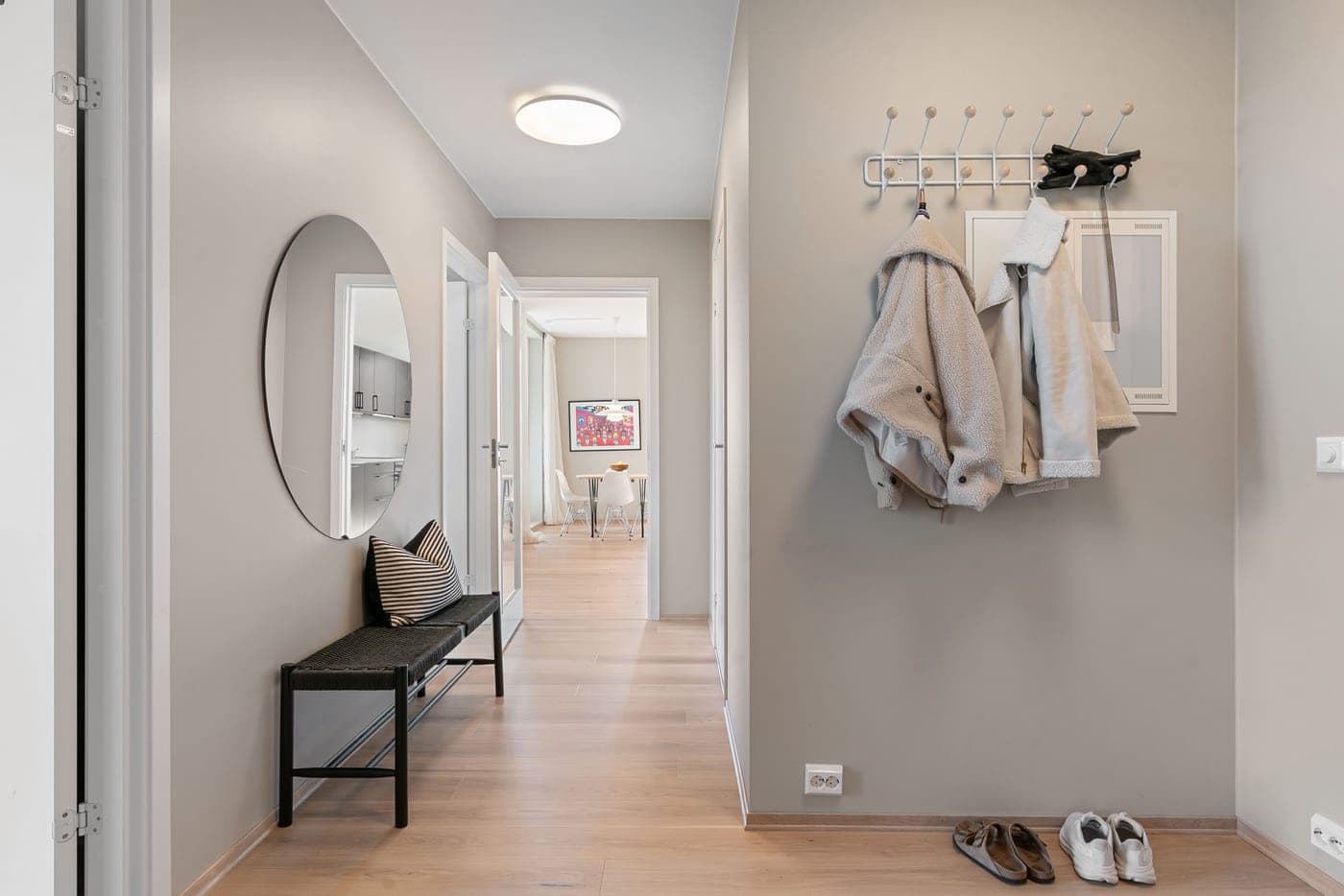 A compact entryway corner with coat hooks above a small bench and shoes below