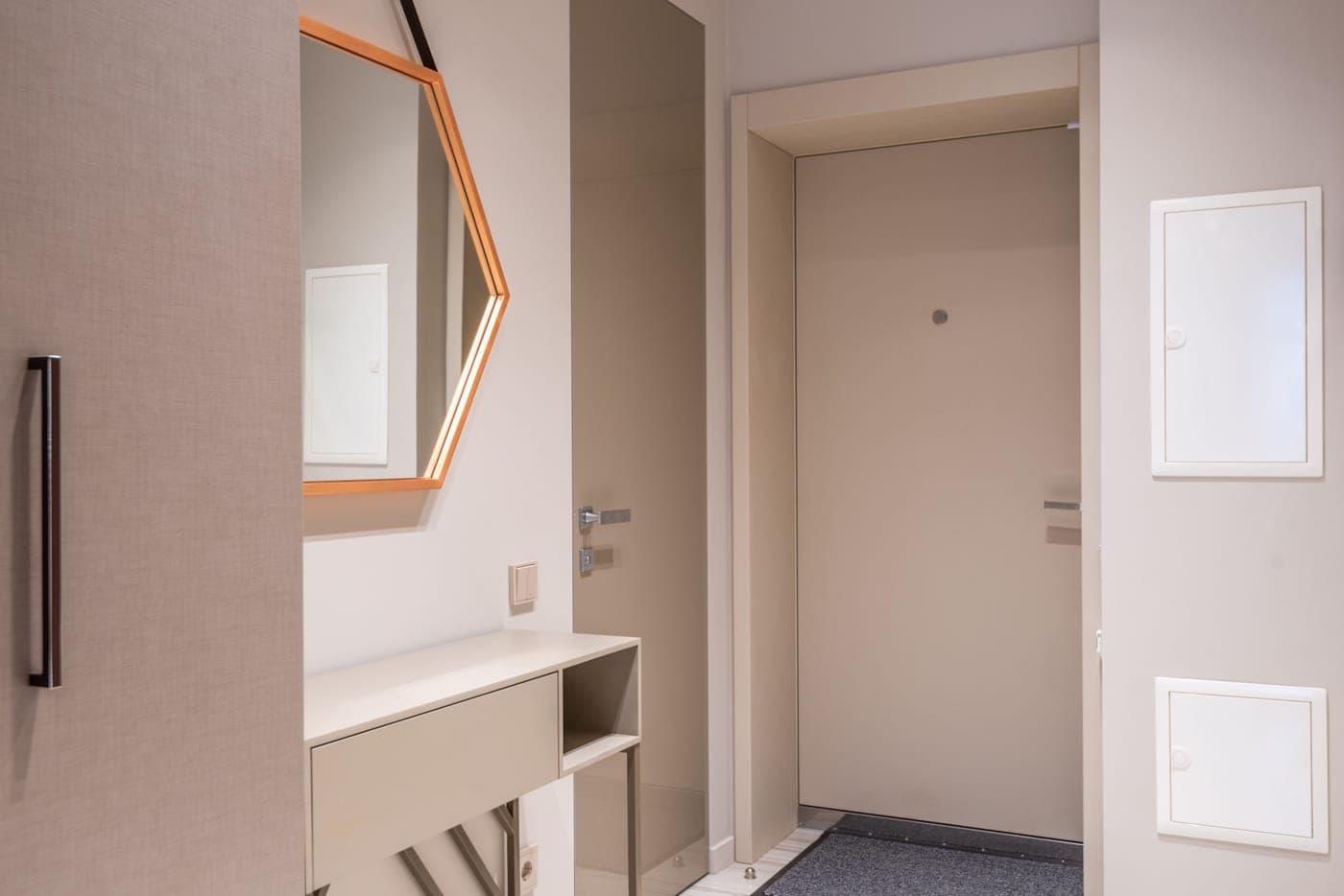 A low cabinet under a hexagonal mirror in a contemporary corridor