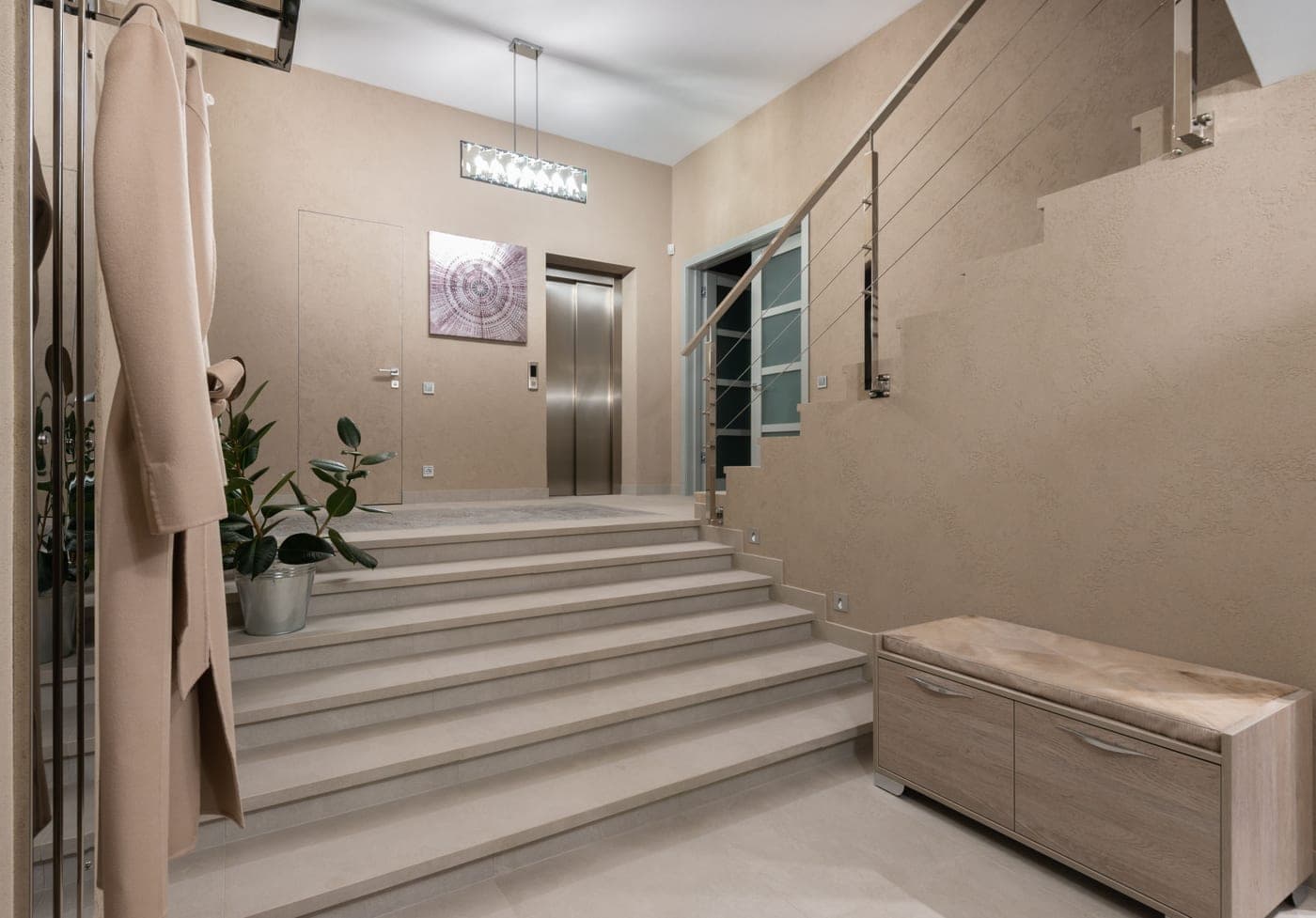 A spacious contemporary hallway with beige walls and a wide stairway