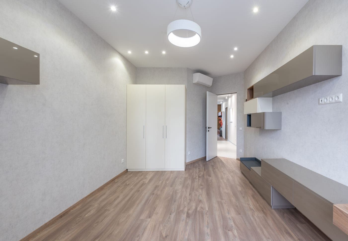 A slim white cabinet standing flush against a wall near an entry door