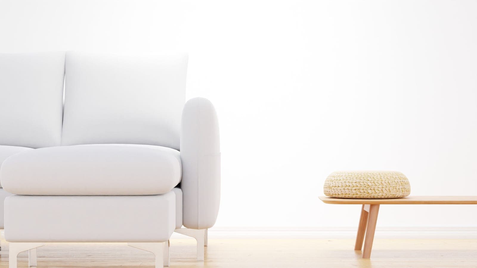 A minimalist living room with a white sofa and a wooden bench with a woven cushion
