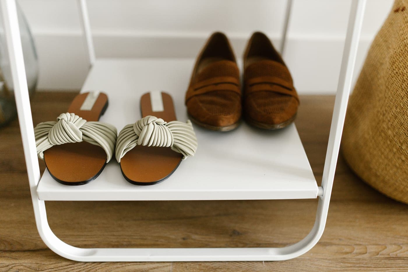 Sandals and loafers arranged on a plain white shelf