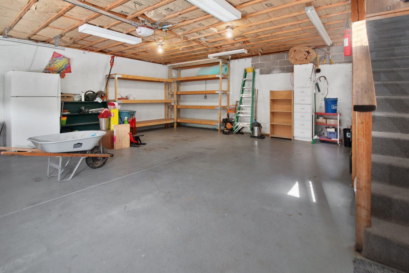 A garage interior with storage shelving and tools along one wall