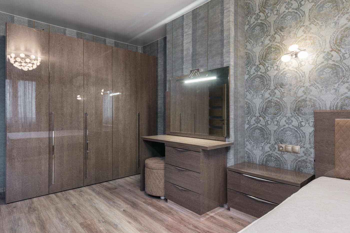 A tall cupboard and chest of drawers standing against a bedroom wall